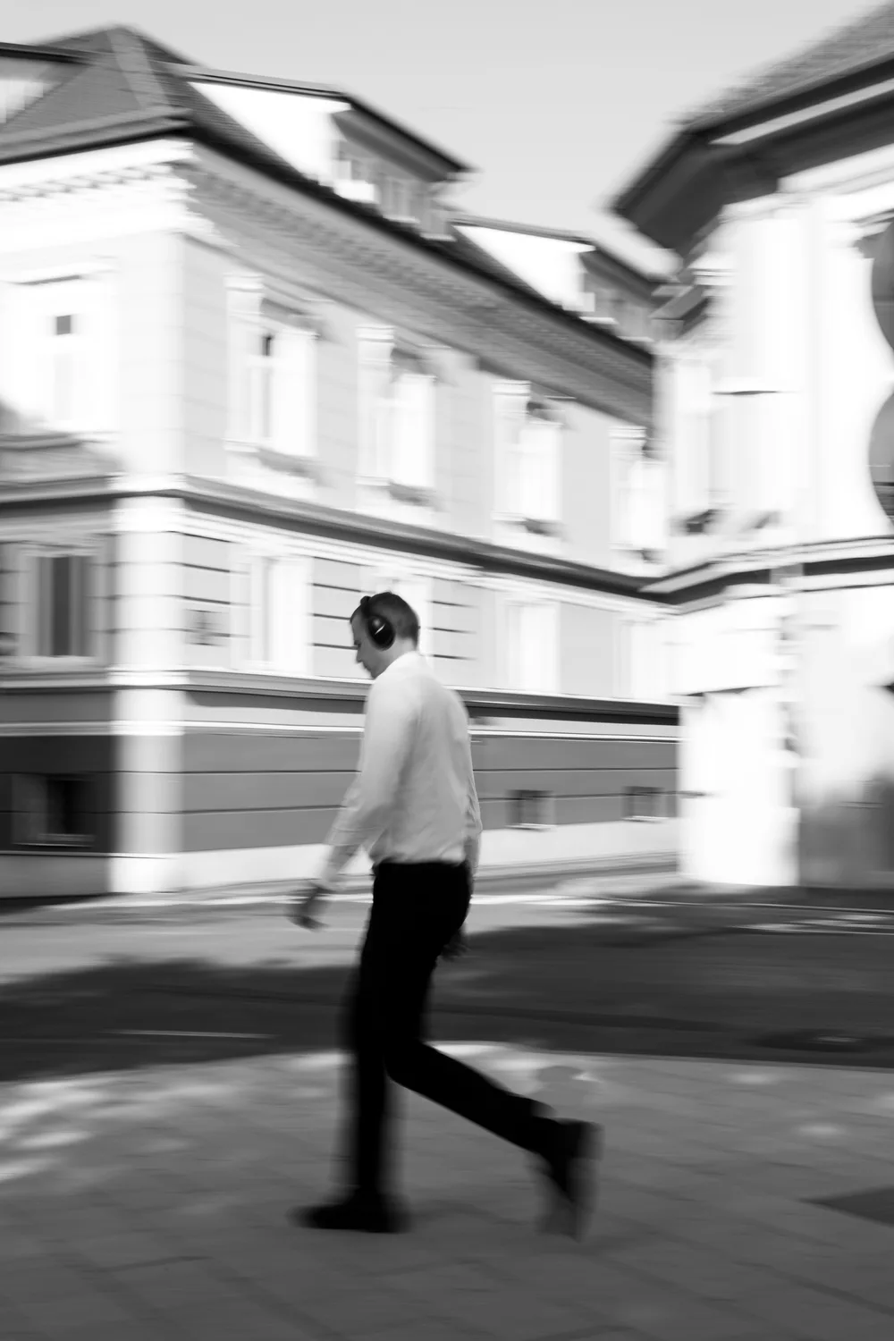 A person wearing headphones walks through a motion-blurred city street.